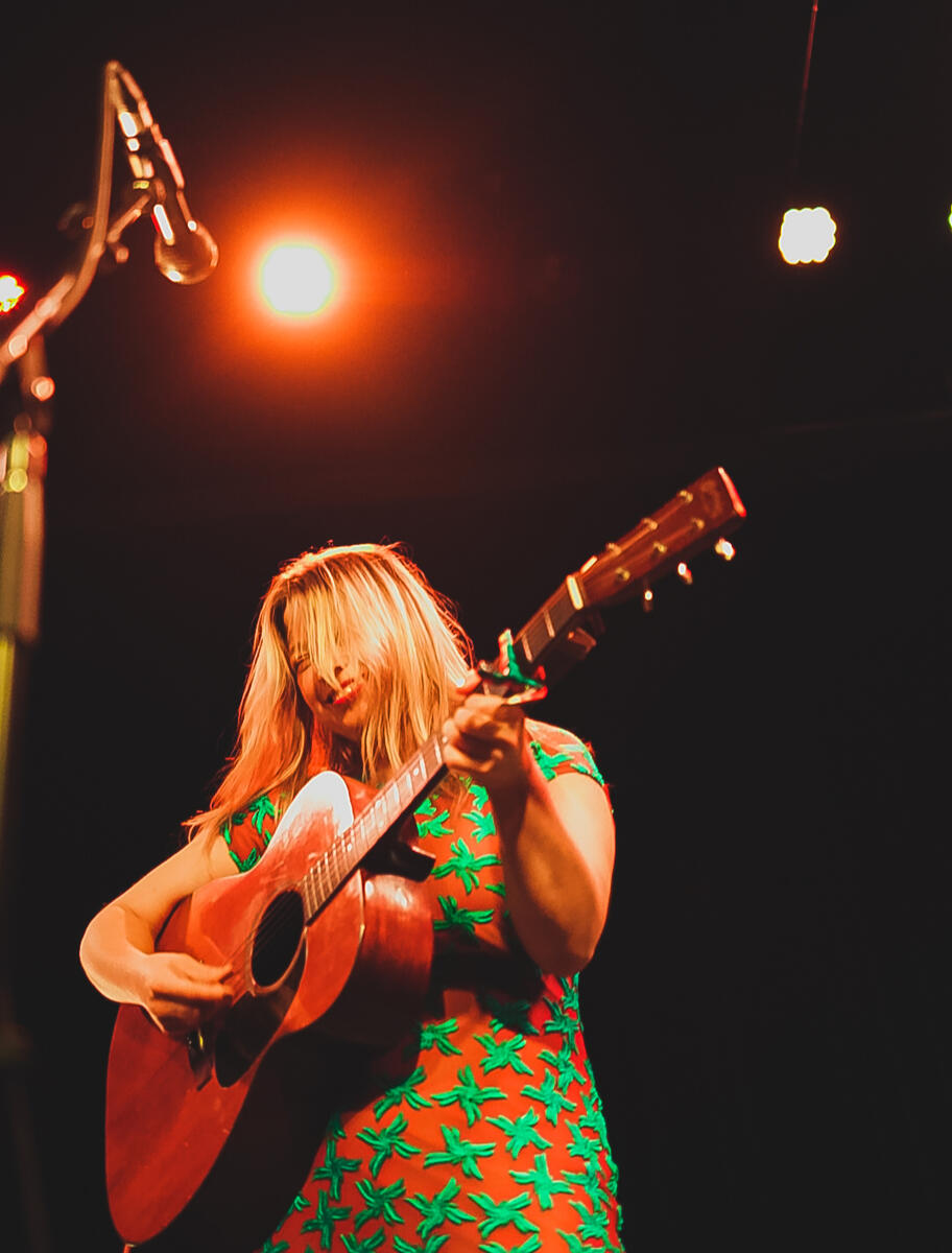 Colour image of female artist playing guitar. Band is "Basia"
