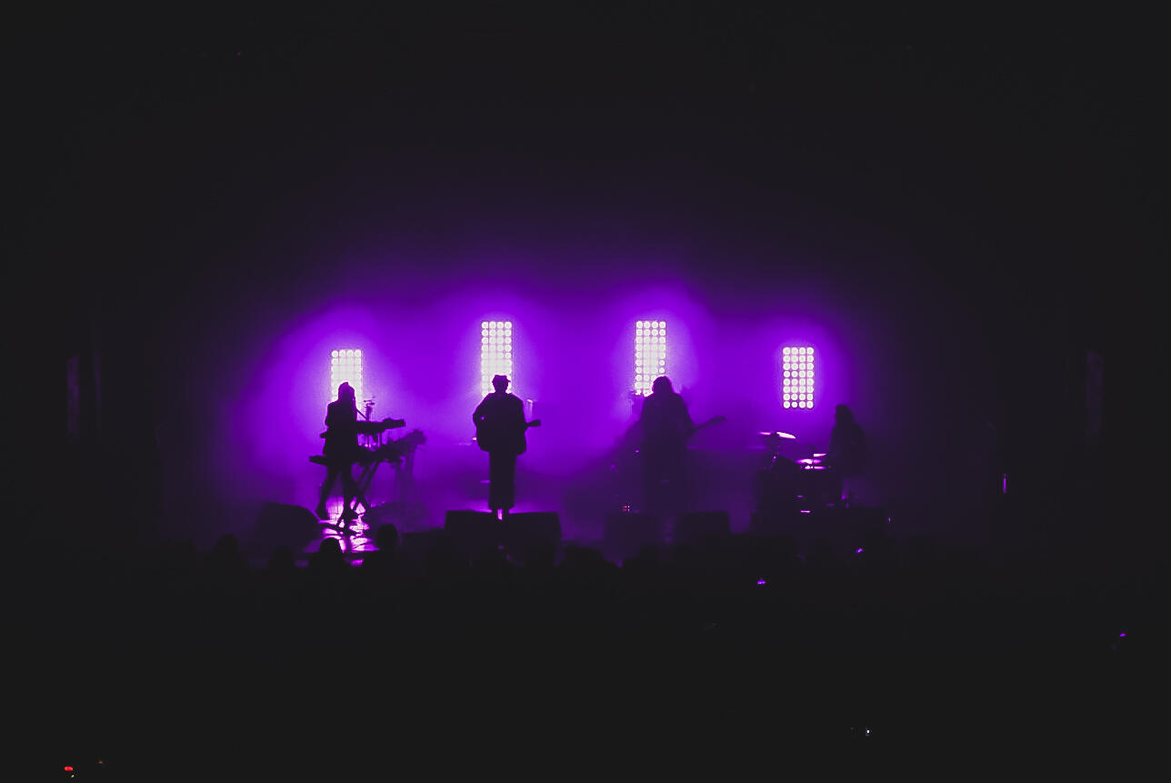 Colour image of band silhouetted by stage lights. Band is "Born Ruffians""