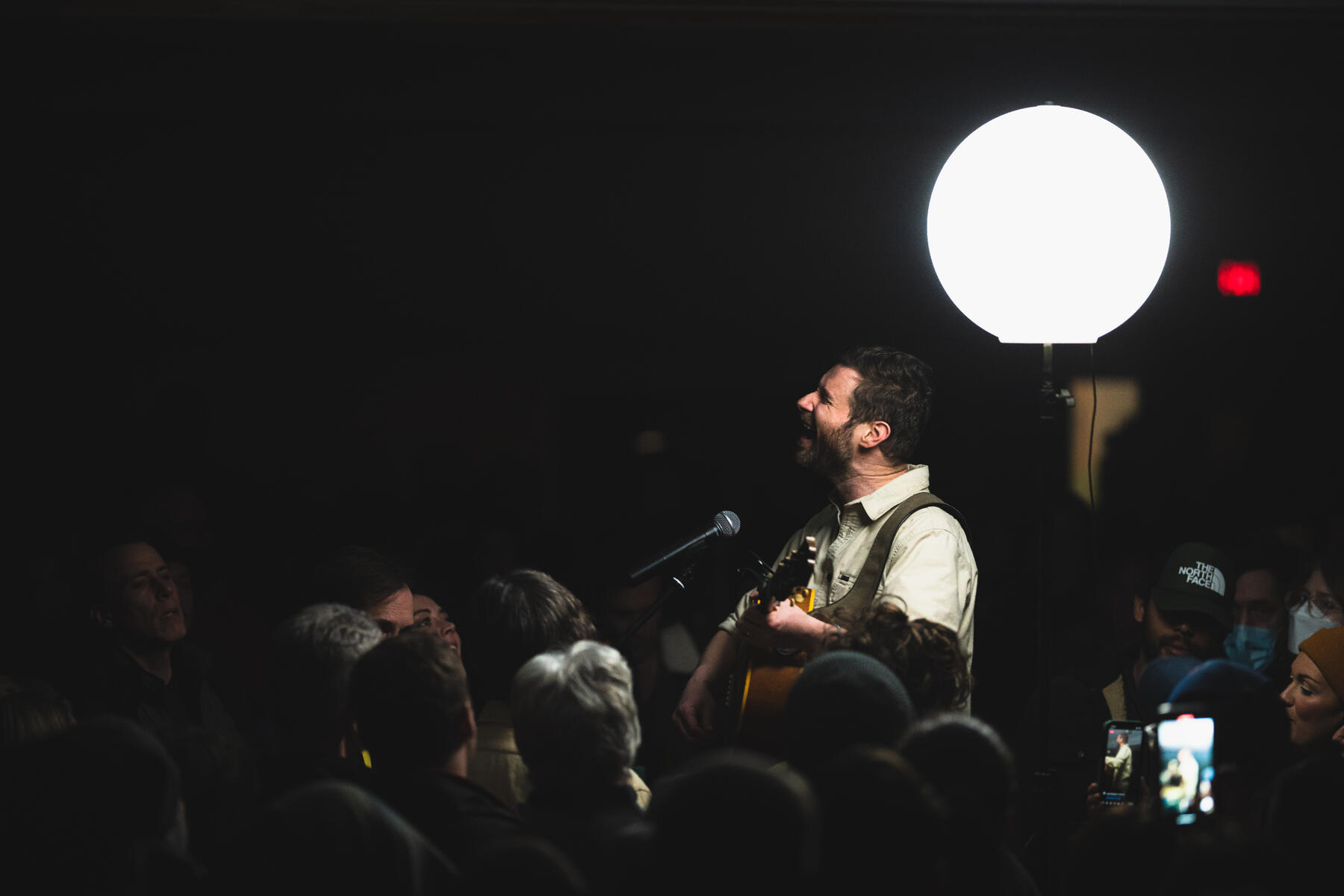 Close up colour photo of lead singer & guitarist singing and strumming in crowd. Band is "Dan Managan"