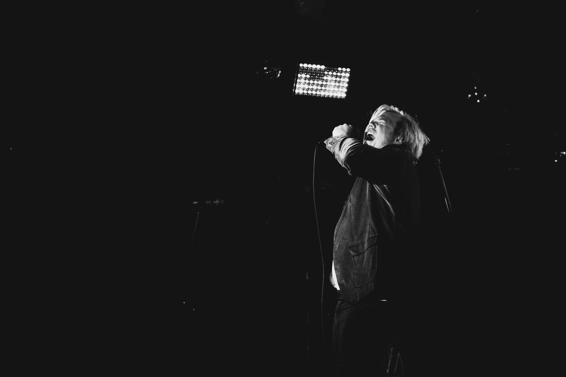 Black and white of lead vocalist singing a key into mic. Band is "Silverstone Hills"