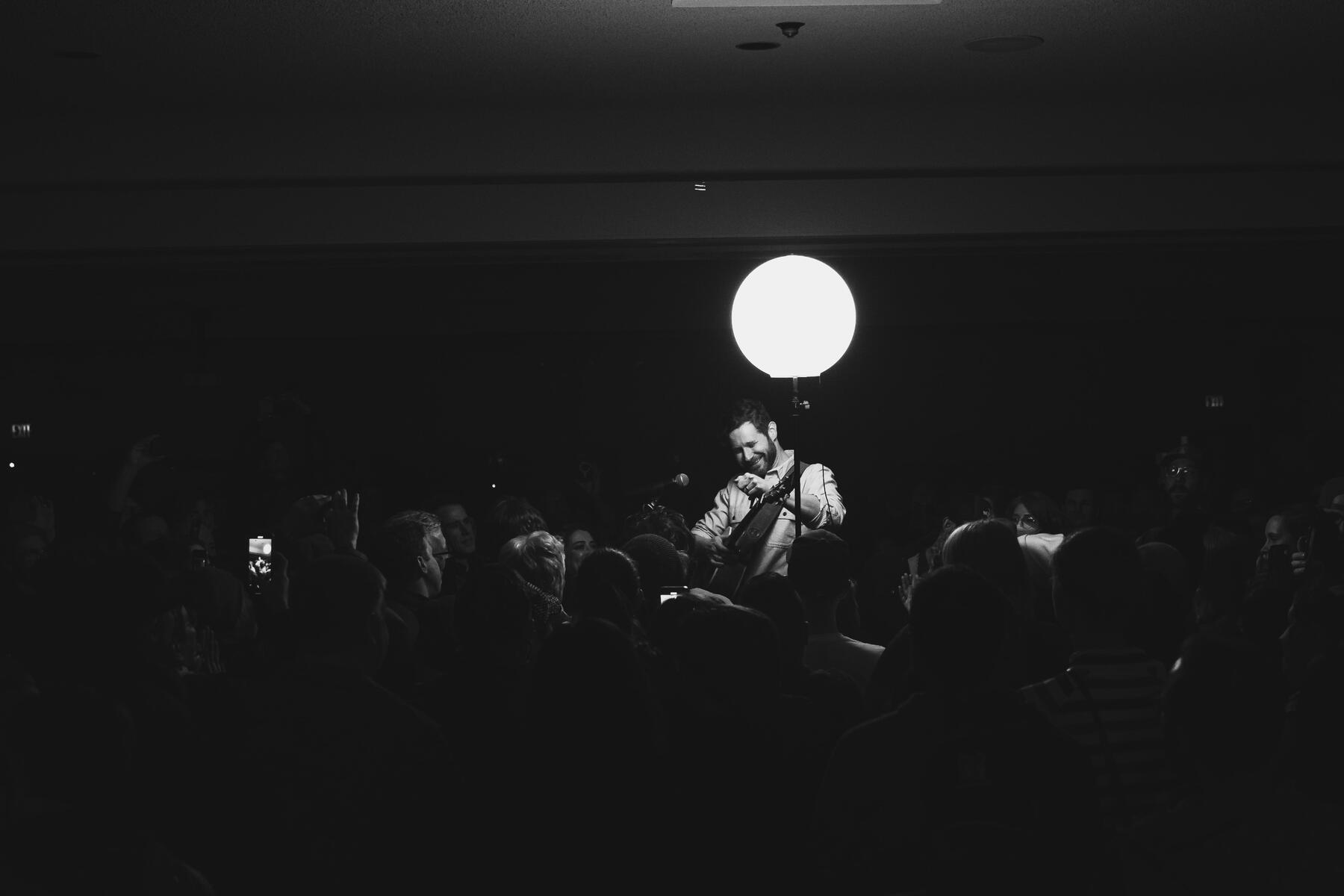 Black and white of lead vocalist and guitar playing in the audience. Band is "Dan Managan"