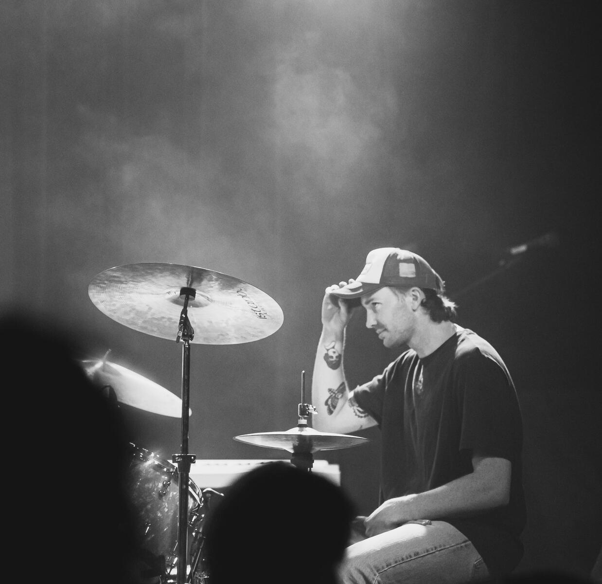 Black and white of drummer tipping his hat while on the drums. Band is "Loviet"